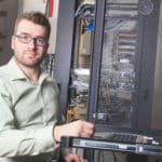 a man in glasses is holding up a computer