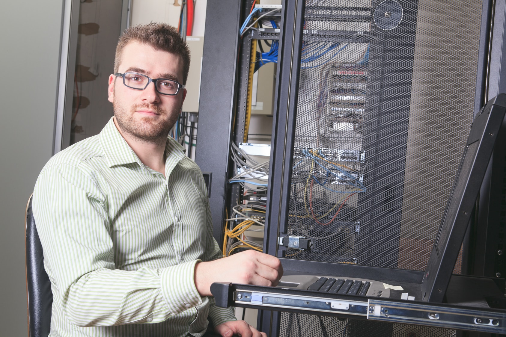 a man in glasses is holding up a computer