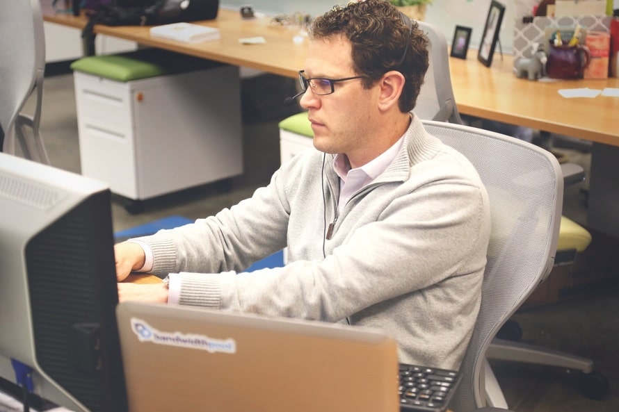 a man sitting in front of a computer monitor