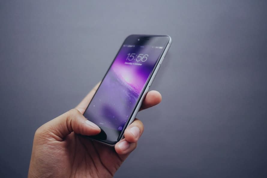 a hand holding an iphone in front of a gray background