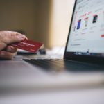 a person holding a credit card in front of a laptop