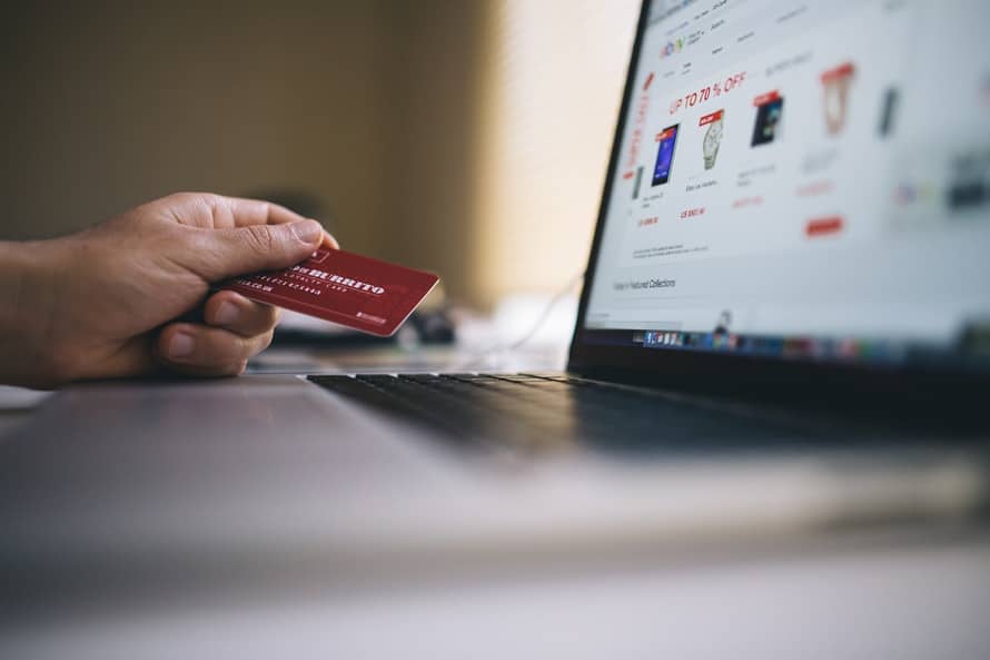 a person holding a credit card in front of a laptop