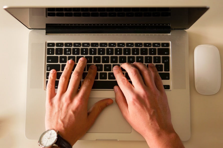 a person typing on a laptop with their hands