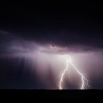 a lightning bolt hitting over a field at night