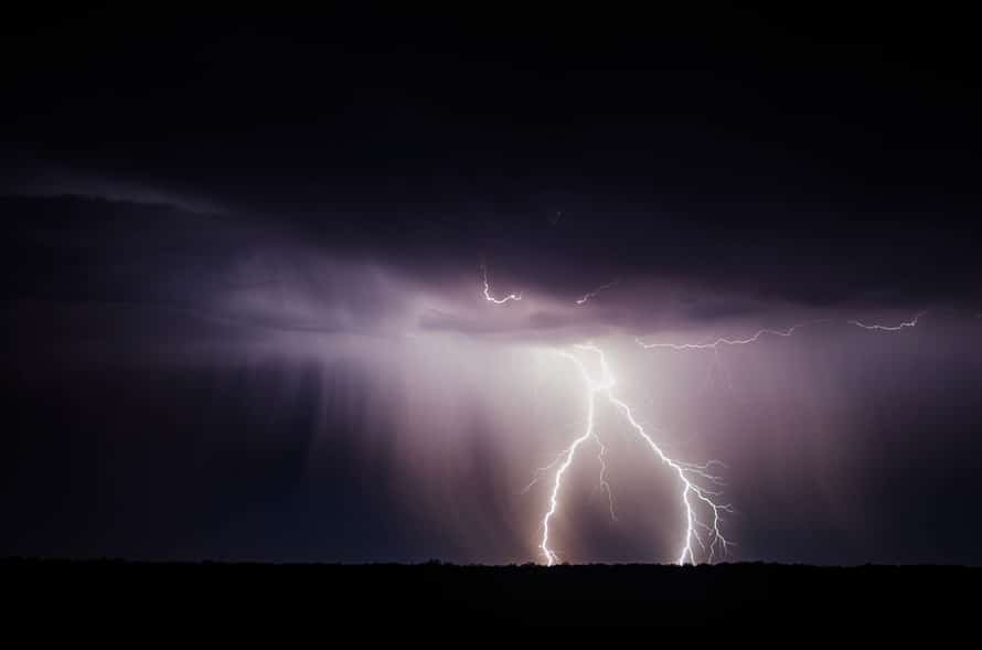 a lightning bolt hitting over a field at night