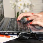 a woman using a laptop computer on top of a desk