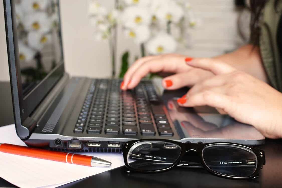 a woman using a laptop computer on top of a desk