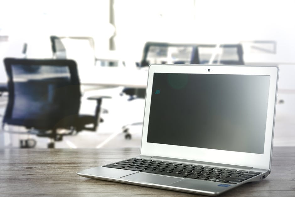 an open laptop computer sitting on top of a wooden table