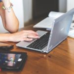 a woman sitting at a table using a laptop computer