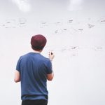 a man writing on a whiteboard with diagrams