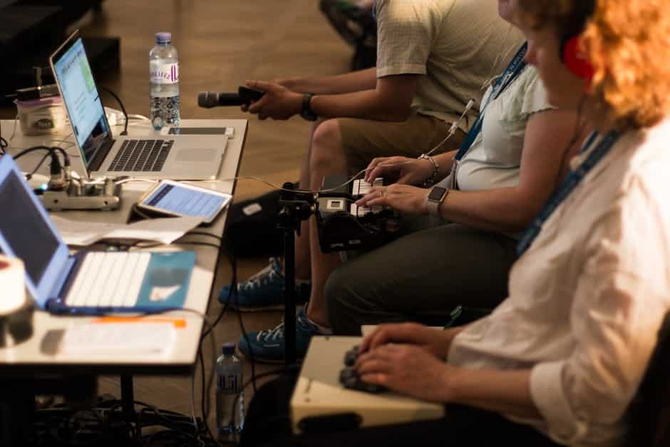 a group of people sitting around a table with laptops