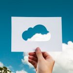 a person holding up a piece of paper with a cloud cut out of it