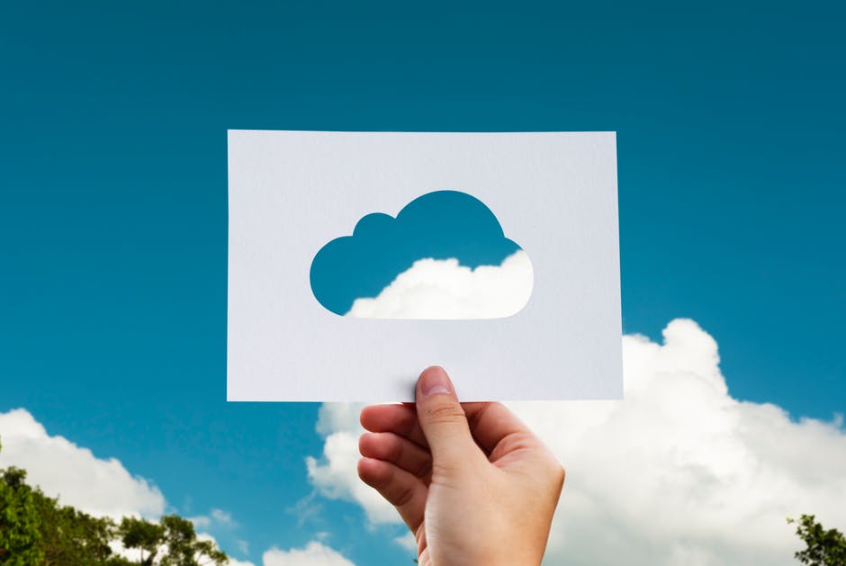 a person holding up a piece of paper with a cloud cut out of it