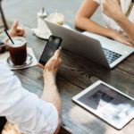 two people sitting at a table with their laptops