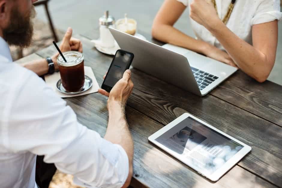 two people sitting at a table with their laptops