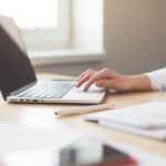 a woman is typing on her laptop computer