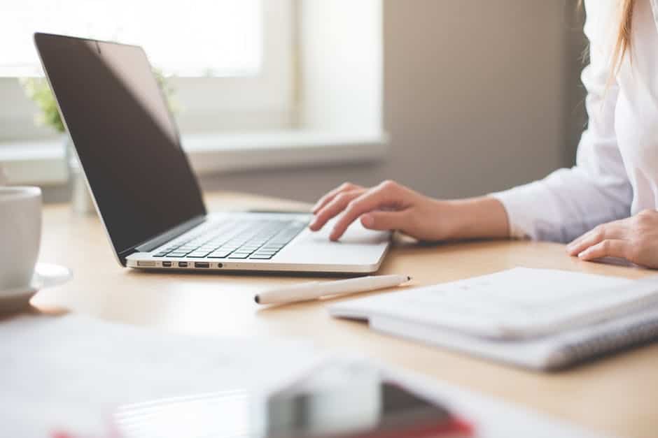 a woman is typing on her laptop computer