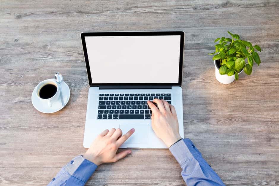 a person using a laptop on a wooden table