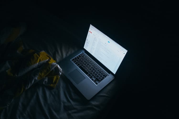 an open laptop computer sitting on top of a bed