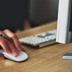 a person using a mouse on a wooden desk