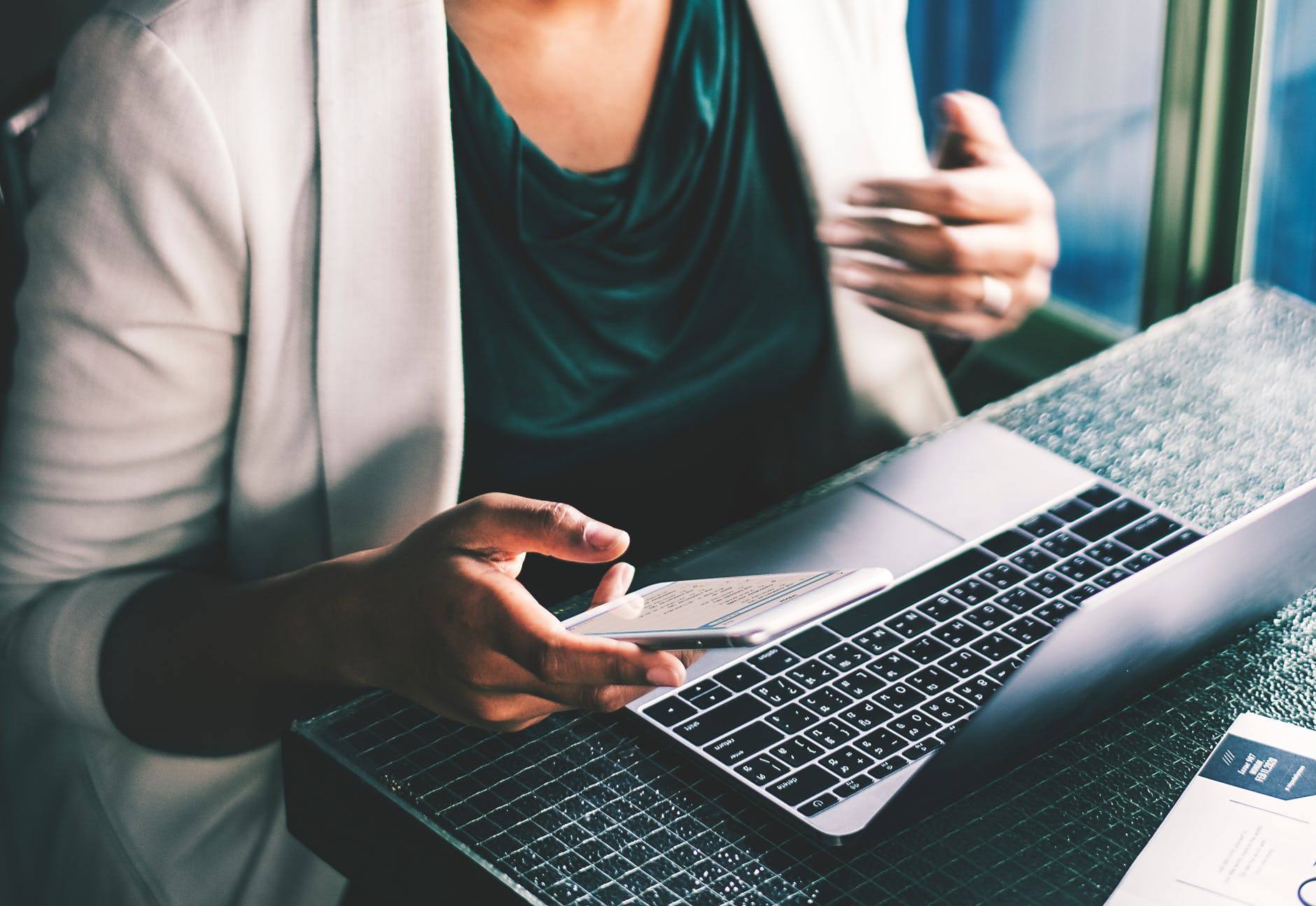 a woman sitting at a table with a laptop and cell phone