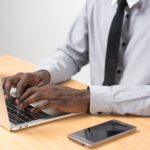 a man sitting at a desk using a laptop computer