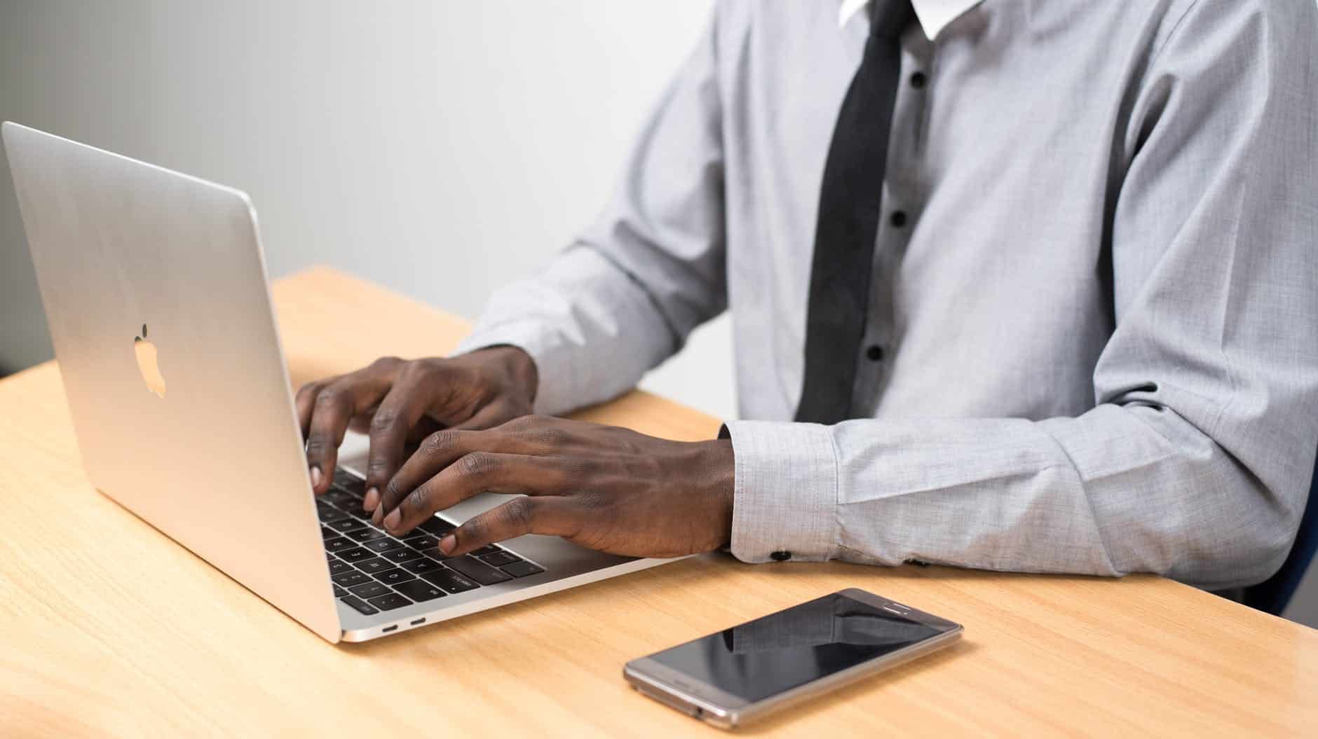 a man sitting at a desk using a laptop computer