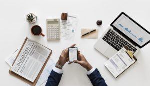 a person sitting at a desk with a cell phone