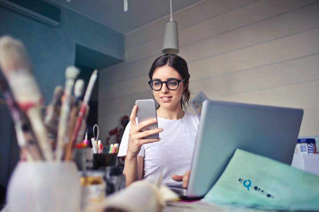 a woman in glasses is looking at her cell phone