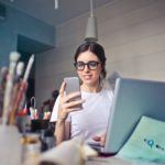 a woman in glasses is looking at her cell phone