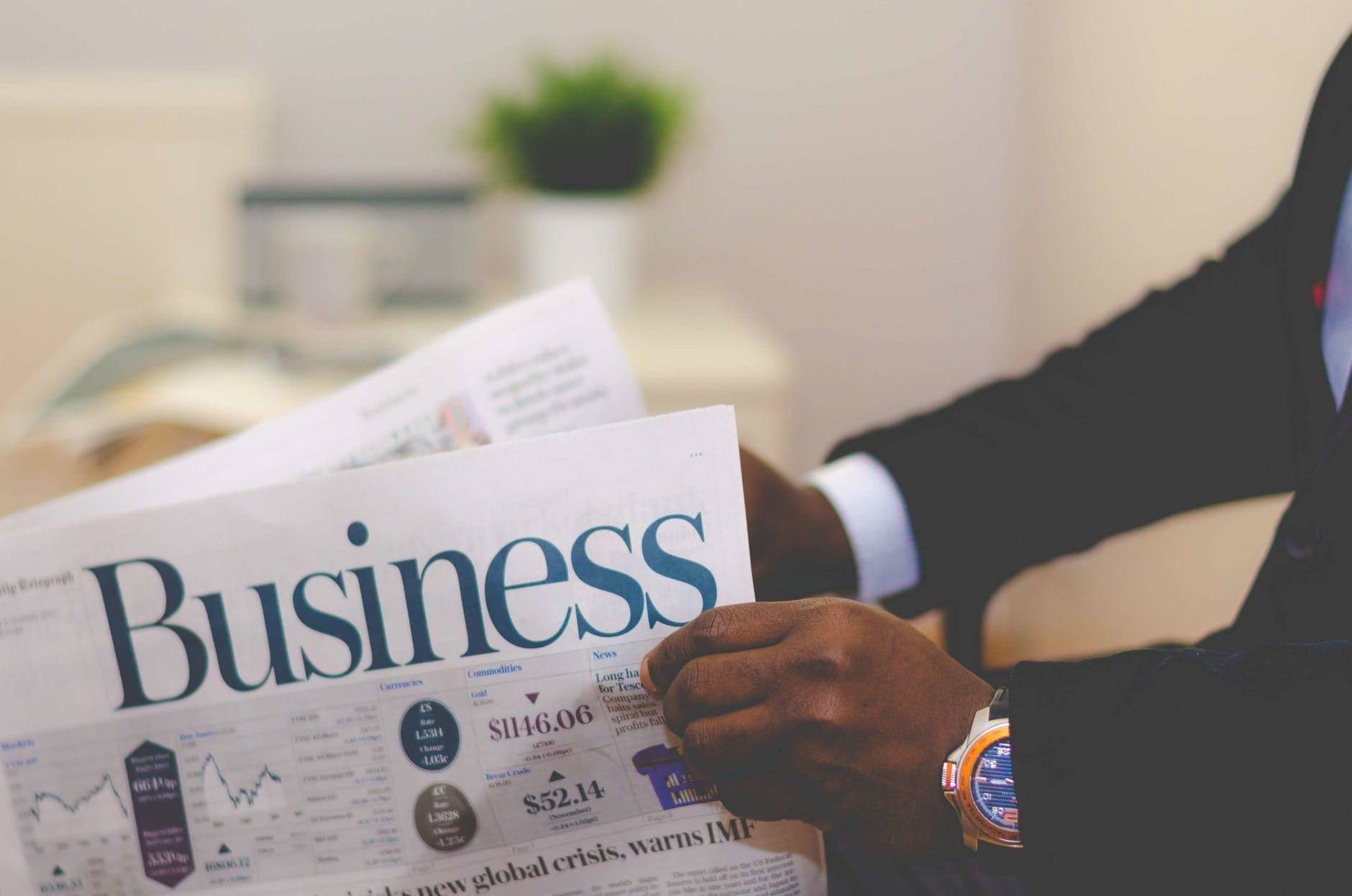 a man in a business suit is reading a newspaper