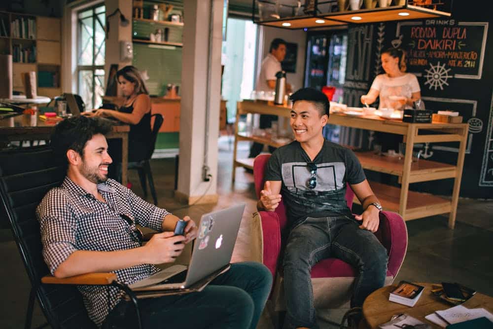 two men sitting in chairs with laptops on their laps