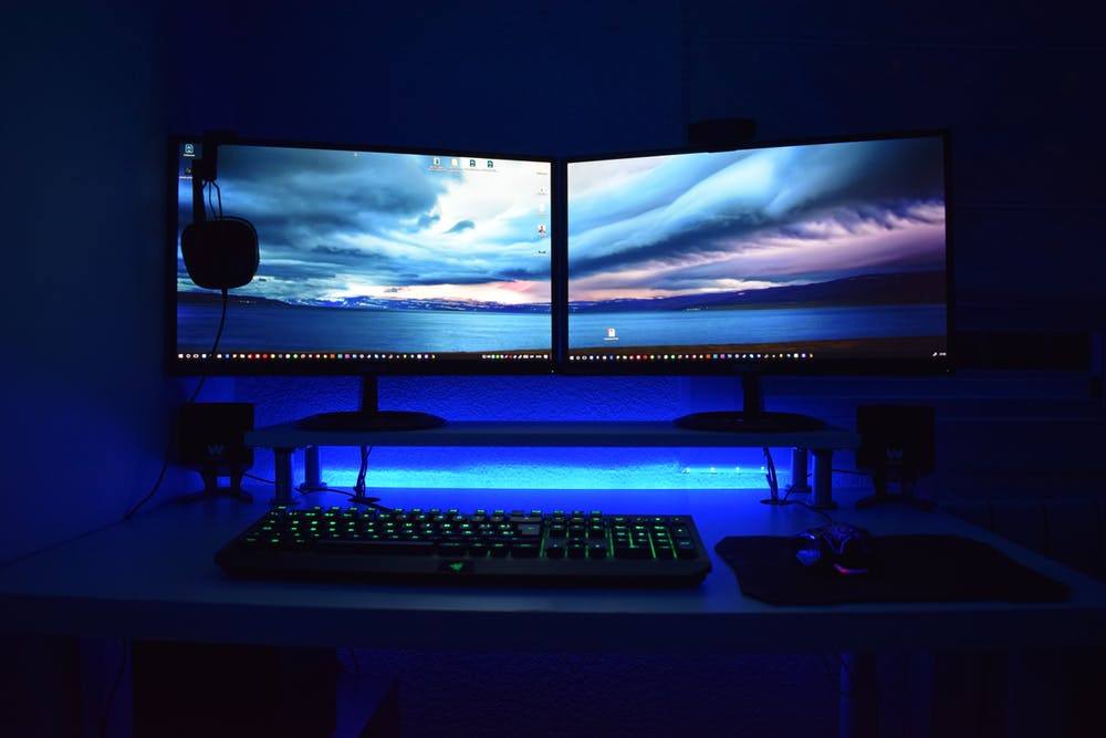 a computer desk topped with two monitors and a keyboard