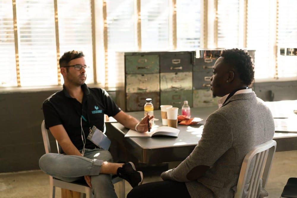 two people sitting at a table talking to each other