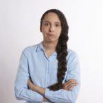 a woman with long hair standing with her arms crossed