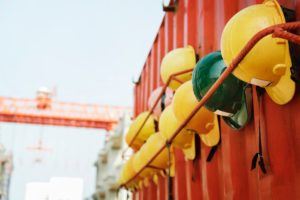 a row of yellow and green helmets hanging on a red wall