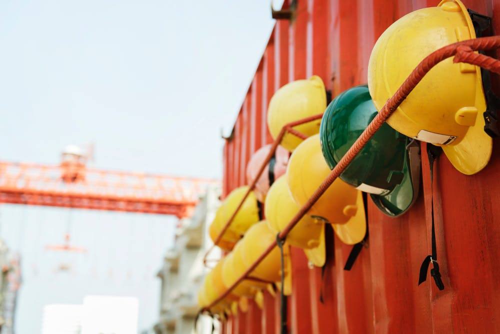 a row of yellow and green helmets hanging on a red wall