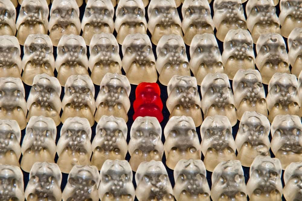 a red object is surrounded by rows of white ones