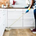 a woman is cleaning the kitchen with a mop