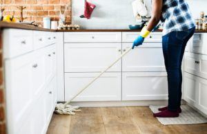 a woman is cleaning the kitchen with a mop