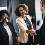 two women shaking hands in an office setting