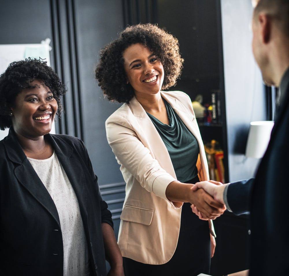 two women shaking hands in an office setting