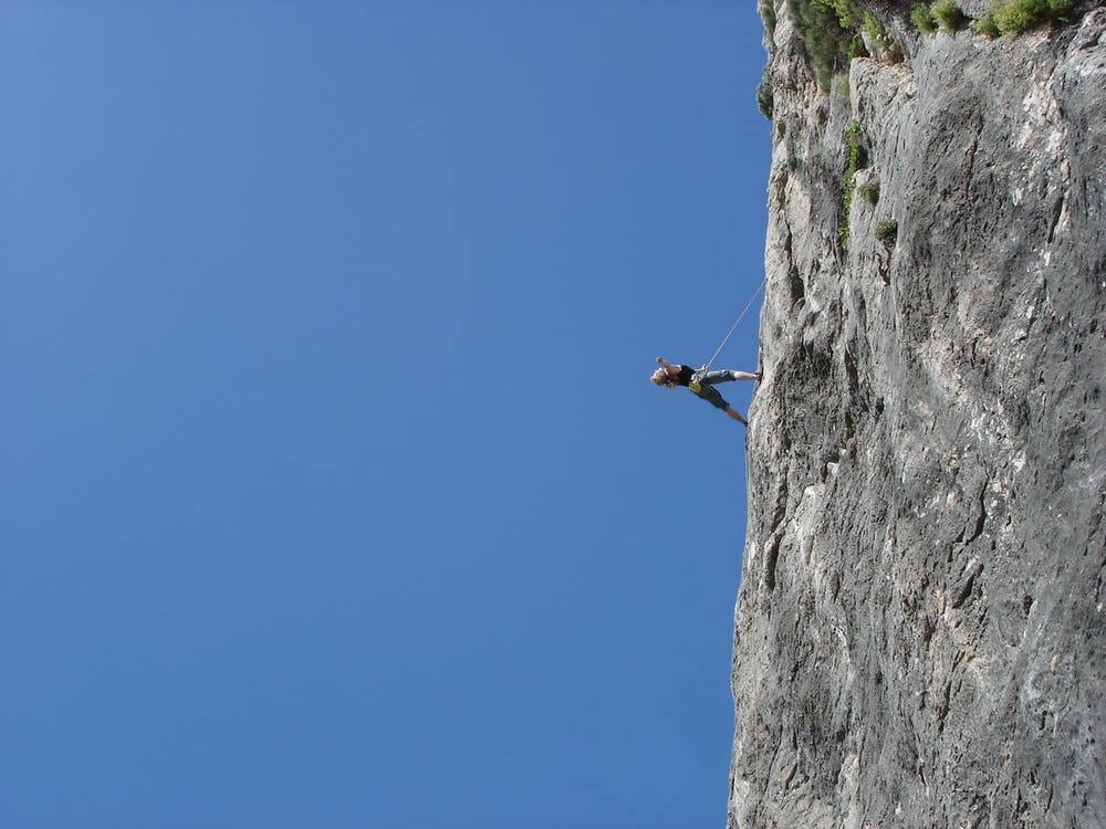 a man hanging from the side of a cliff