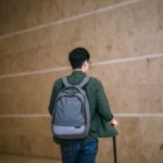 a man with a backpack and suitcase walking