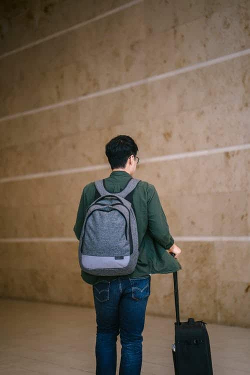a man with a backpack and suitcase walking