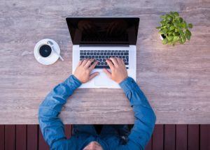 a person sitting at a table using a laptop computer