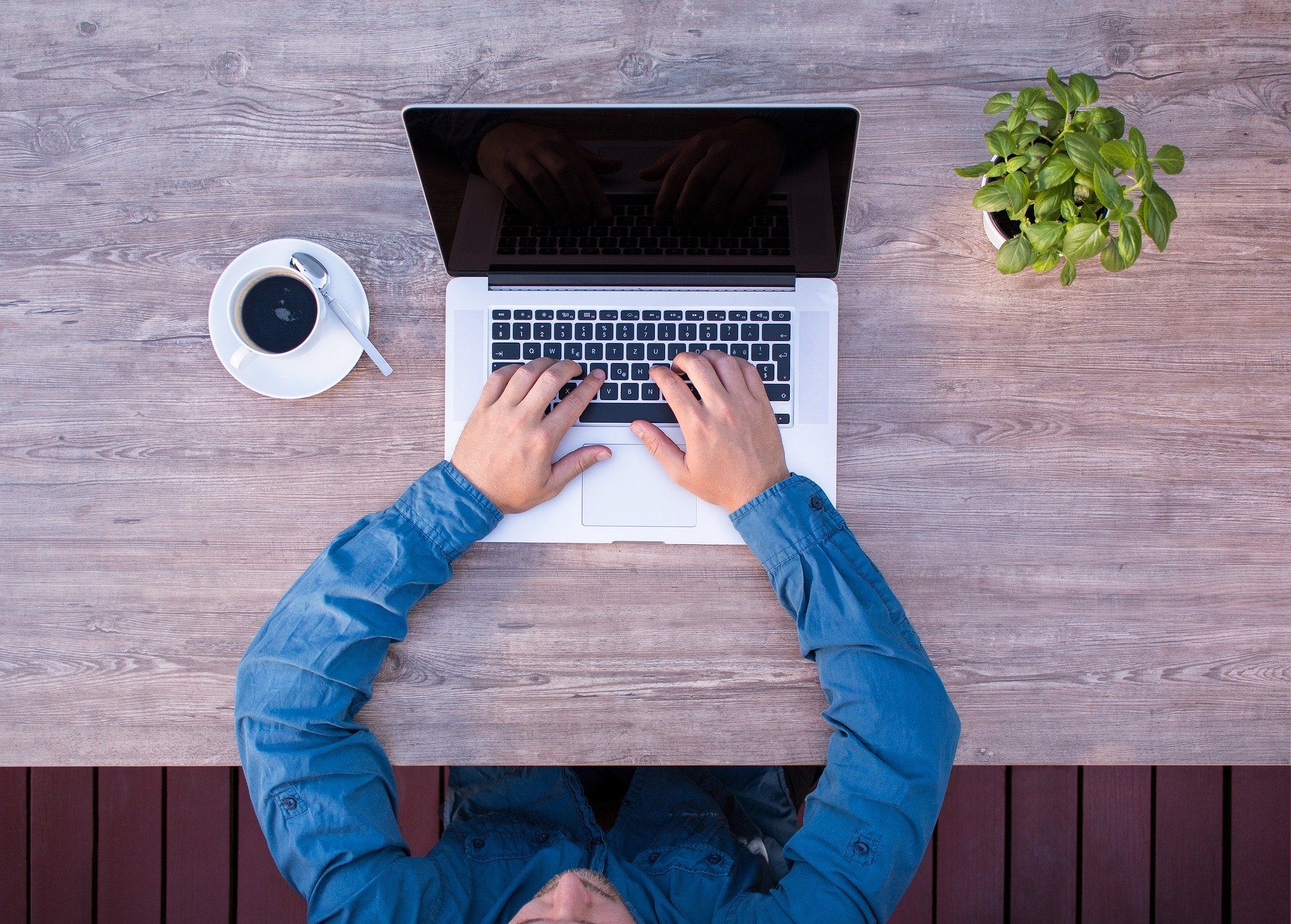 a person sitting at a table using a laptop computer