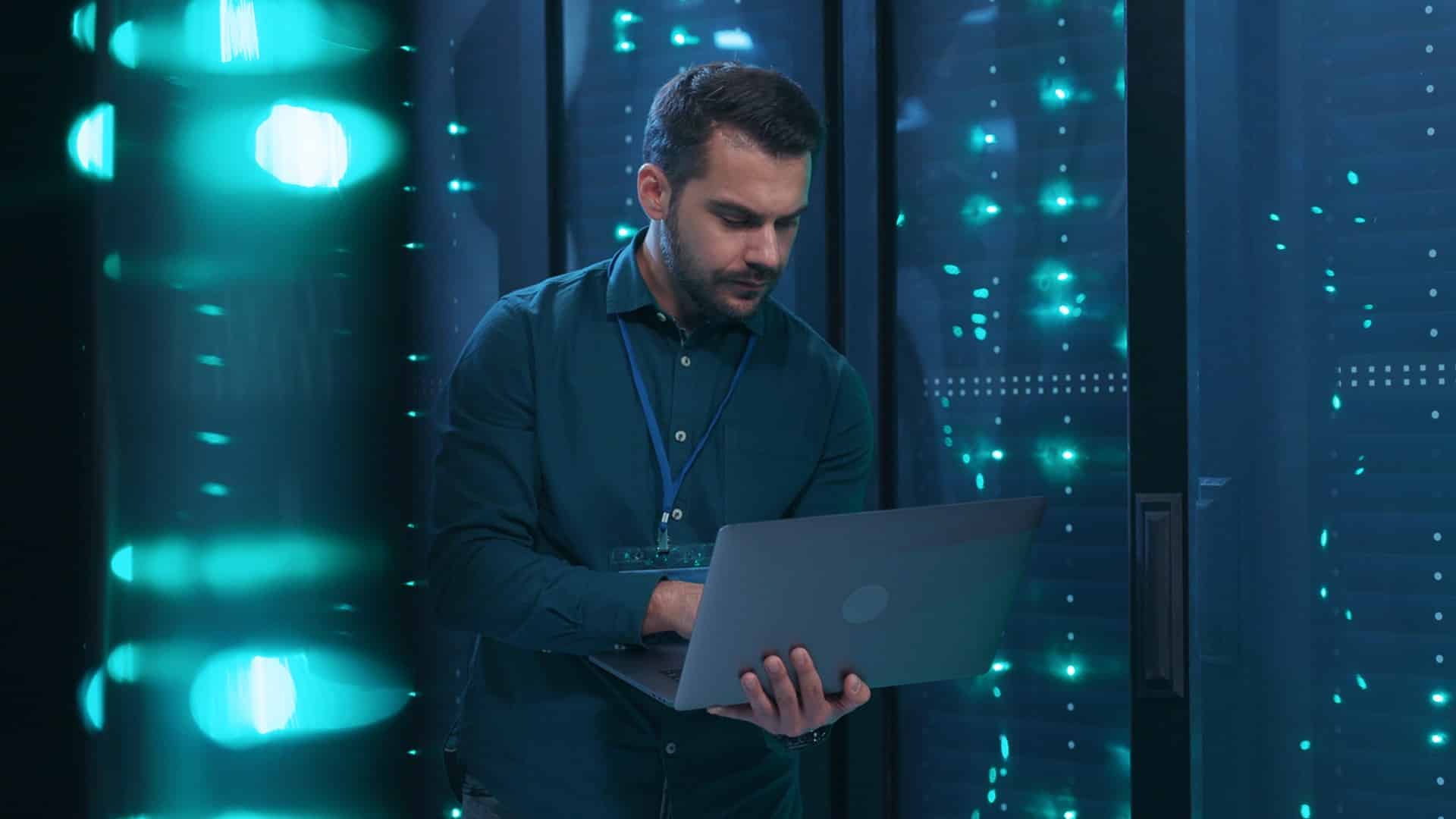 a man is looking at his laptop in the server room