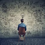 a person sitting in a chair looking at a wall with drawings on it