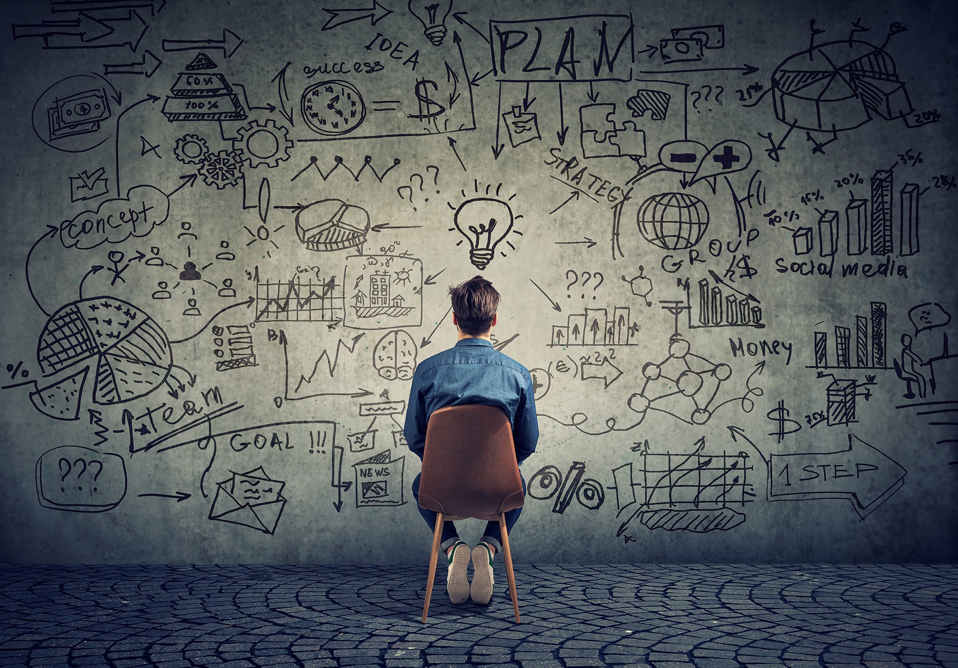 a person sitting in a chair looking at a wall with drawings on it